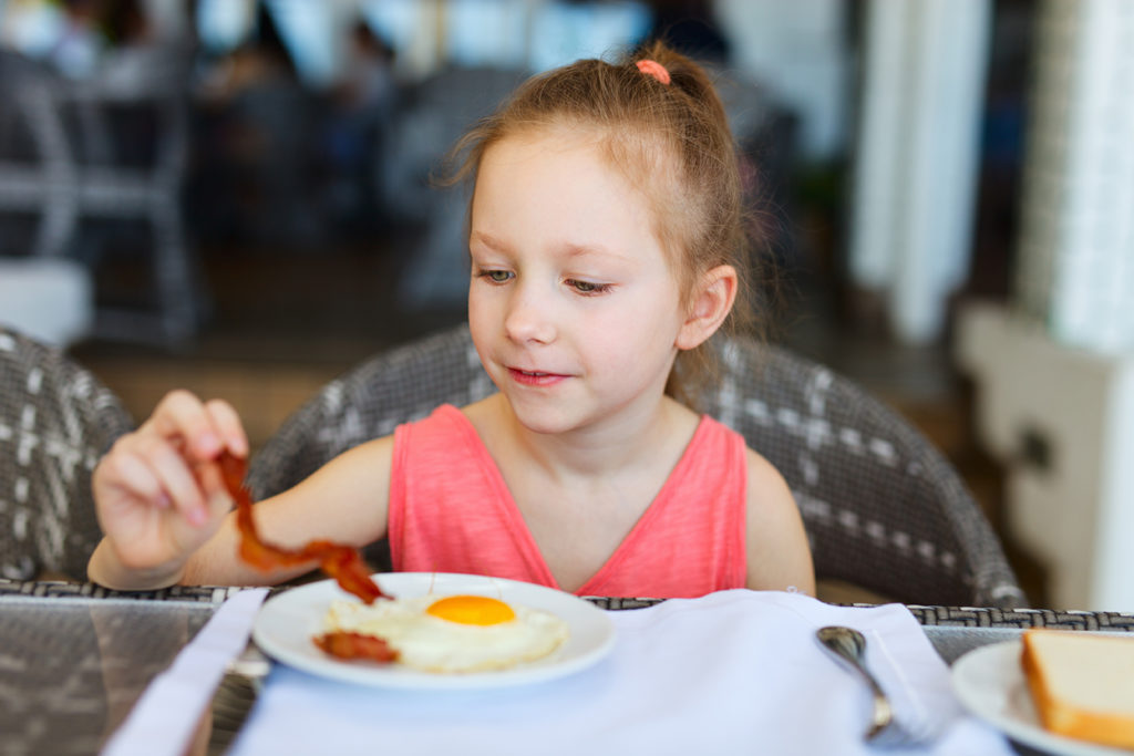 young girl enjoying bacon and eggs