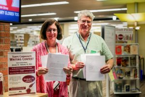 Tempe Librarians Jill Brenner and Rolf Brown display some of the early entries in a writing competition open to all ages. Entries must be received by Feb. 15. — [Wrangler News/Billy Hardiman]