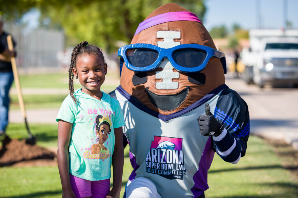 Girl poses with Spike, the Arizona Super Bowl Host Committee mascot.