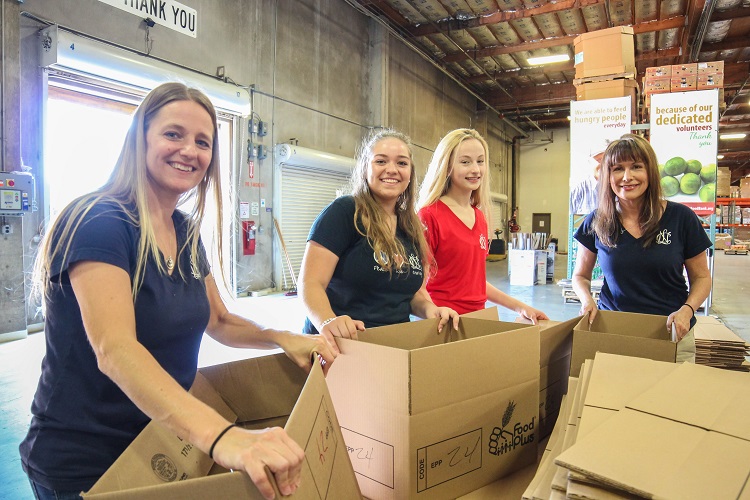 There were smiles all around as volunteers from the East Valley chapter of National Charity League packed food boxes for the elderly St. Mary's Food Bank. Group included, from left, mom Michele Nichols and daughter Jill with Cate Baskin and her mom, Mona. 