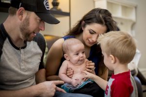 Dad Andy, Mom Elyse and little brother Jake at home with the newest addition to their family. The scars will remain a lifelong reminder of Baby Jackson's miracle recovery. [Billy Hardiman/Wrangler News]